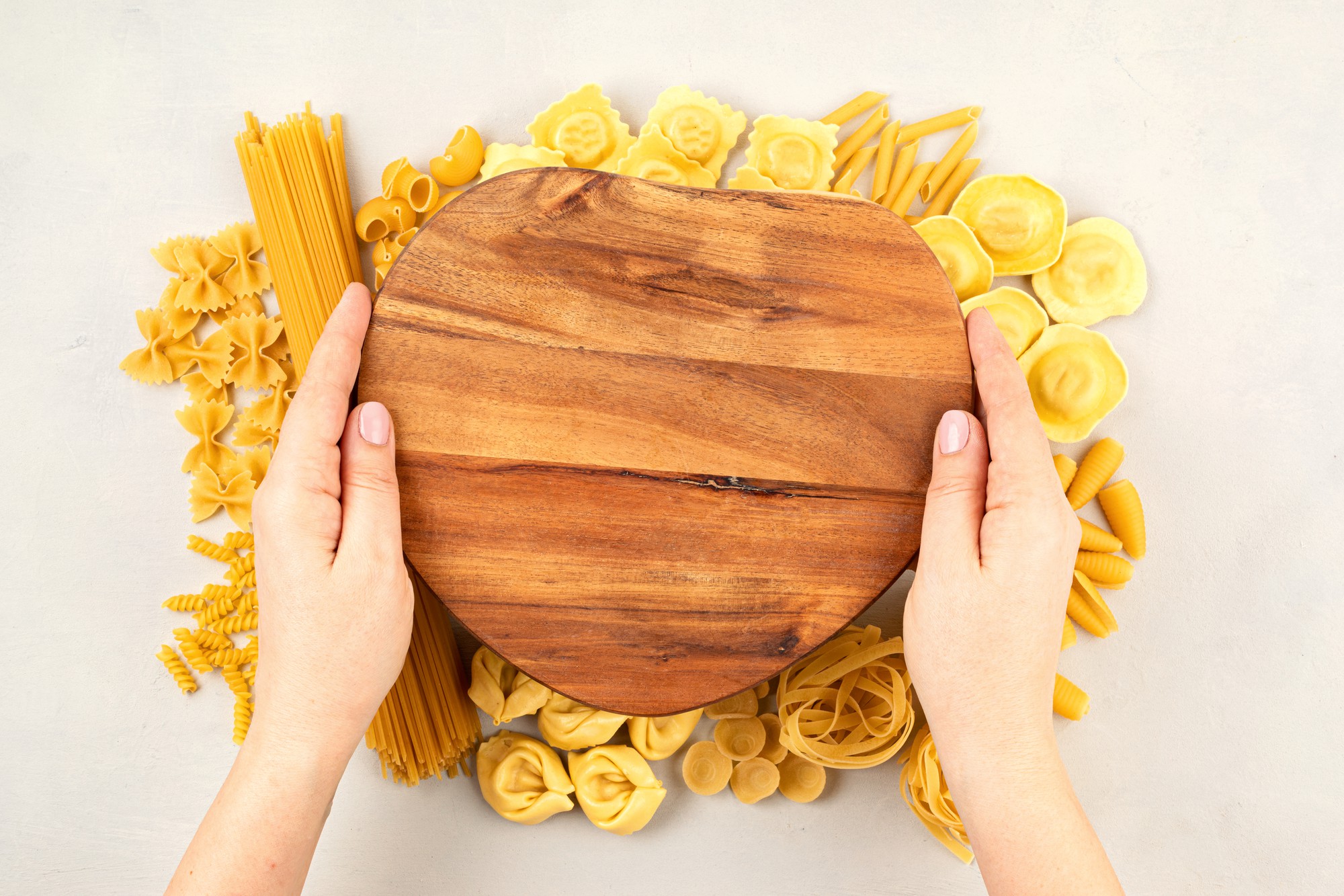 Handmade pasta being shaped on wooden board